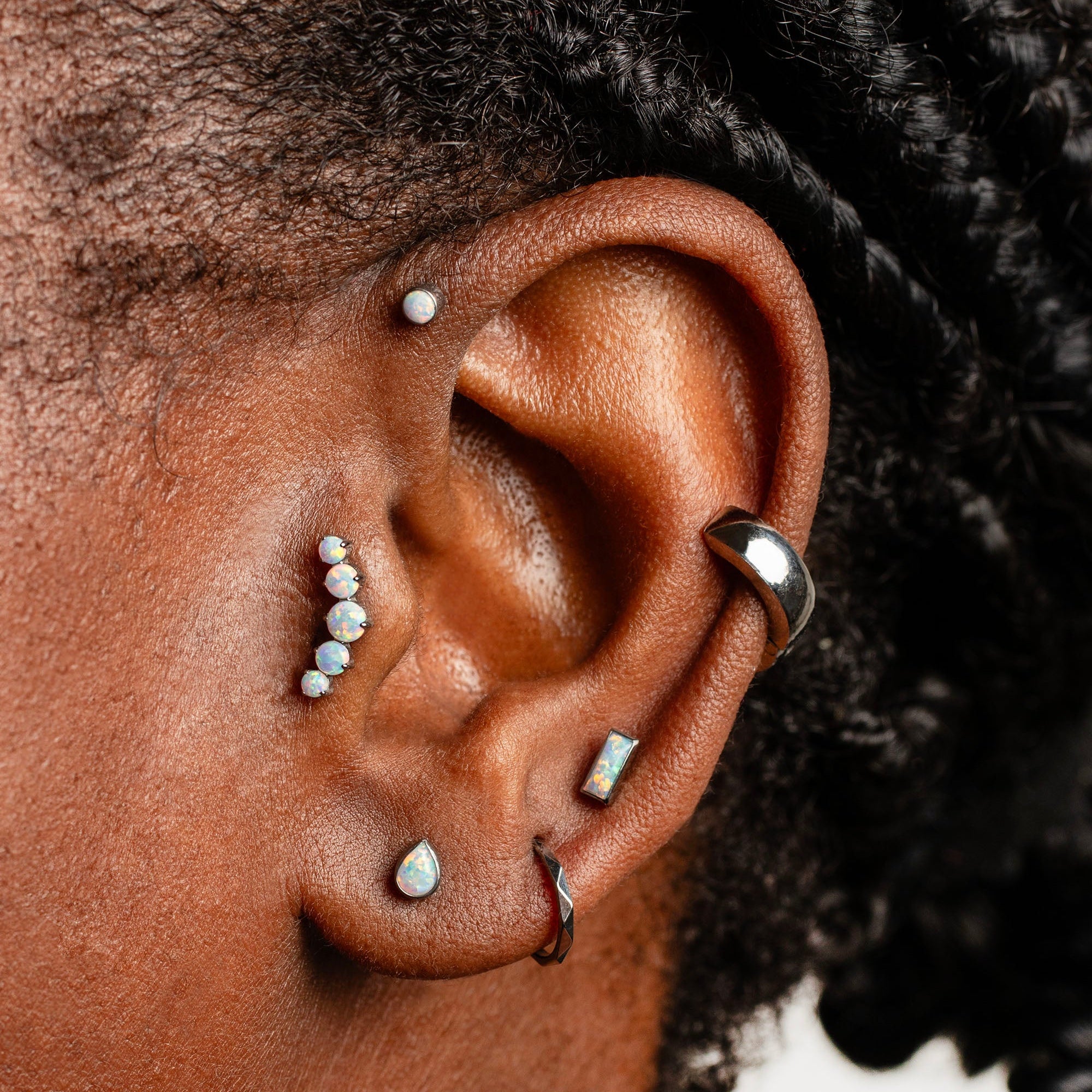 Close-up of an ear with multiple earrings on a blurred background