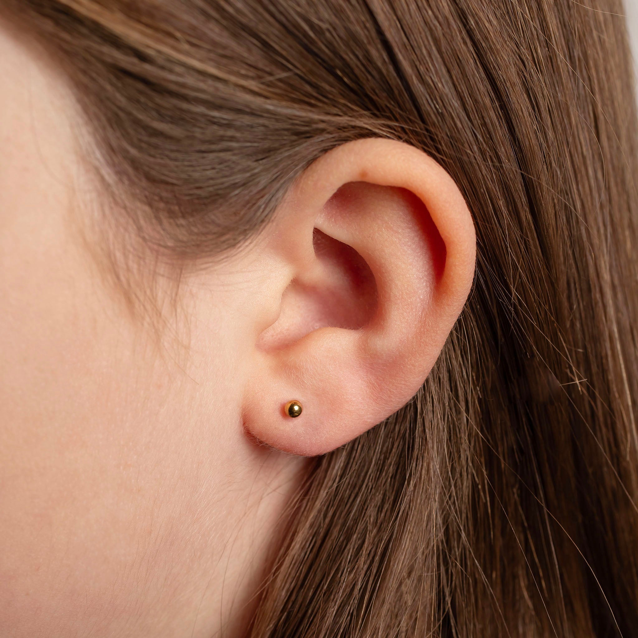 Close-up of an ear with a small black earring.